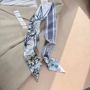 Dettaglio macro di un foulard twilly in seta con stampa botanica su un blazer kaki
