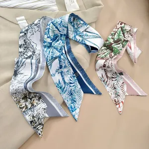 Dettaglio di tre sciarpe in raso con stampe botaniche drappeggiate su un blazer beige