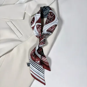 Dettaglio di un foulard sottile in seta paisley abbinato a un blazer beige elegante