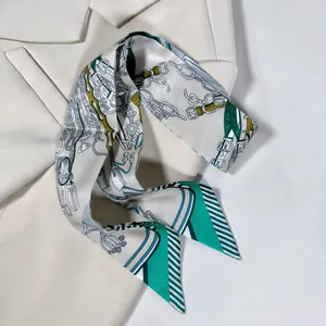 Gros plan d'un long foulard en soie à motif mors vert sur une veste beige