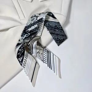 Dettaglio di una sciarpa in seta sottile bianca e nera su un blazer beige