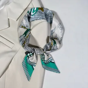 Détail du foulard en soie vert émeraude et or avec motifs de mors et chaînes élégants