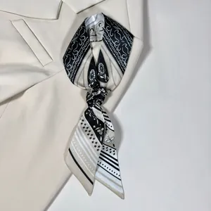 Dettaglio di una sottile sciarpa di seta con motivi paisley annodata su un blazer