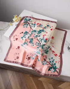 Detailed close-up of pink and beige silk scarf with floral cherry blossom print and satin sheen