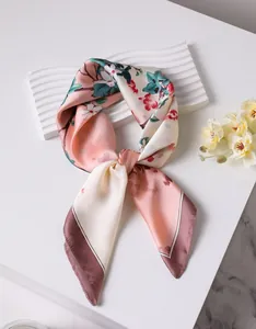 Detailed close-up of a floral silk scarf with retro patterns and elegant crimson edging