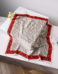 Vue détaillée du foulard carré en satin soyeux à motif paisley et bordure rouge