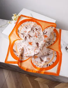 Detailed close-up of silk scarf with orange floral print and elegant petal pattern