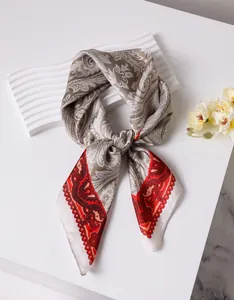 Détail macro d'un foulard en soie aux motifs paisley complexes et aux bords rouges élégants