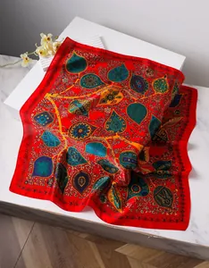 Detailed close-up of a red bohemian paisley silk square scarf on elegant display marble