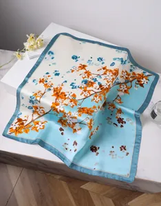 Detailed close-up of orange floral print on a blue and white satin square scarf