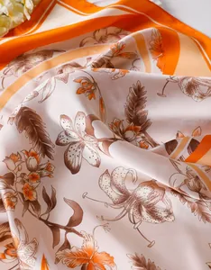 Detail of silk-like satin square scarf with orange floral lily and feather prints