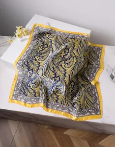 Détail d'un foulard en soie paisley jaune et bleu sur une surface en marbre
