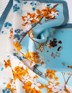 Macro detail of high-quality floral silk scarf showing blue-orange print and smooth texture