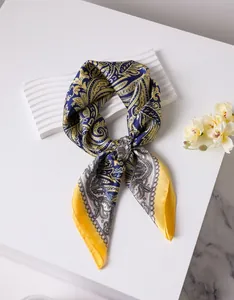 Gros plan d'un foulard en soie bleu et jaune avec motif paisley sur support élégant
