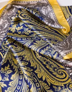 Vue détaillée du foulard en soie jaune et bleu avec motif paisley et texture satinée