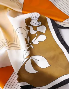 Detail of satin floral scarf showing smooth silk texture and artistic orange patterns