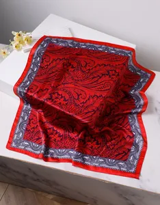 Détail du foulard carré en soie rouge avec motifs paisley et reflets soyeux