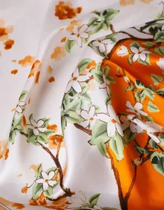Detail of silk scarf showing floral print and smooth drape of the orange-white fabric