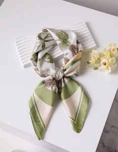 Detailed close-up of a floral silk scarf tied in a bow with tropical leaf prints