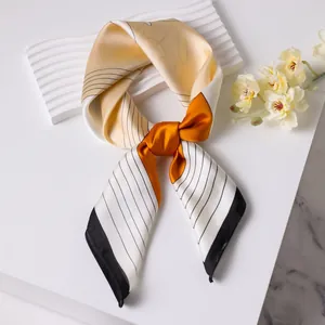 Elegant floral silk scarf in beige and yellow with black stripes on a marble surface