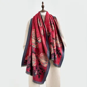 Détail d'une écharpe rouge à motif rose vintage avec franges et toucher cachemire épais