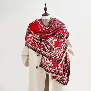 Detailed view of red paisley cashmere shawl draped over a beige wool coat on a mannequin