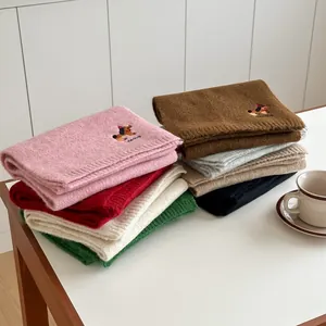 Dettaglio del ricamo a forma di cane e trama in maglia su sciarpe invernali colorate