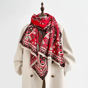 Detail of red paisley cashmere-feel scarf with fringe edges and ethnic floral patterns