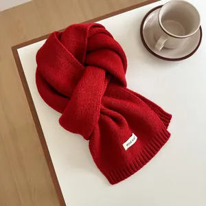 Macro detail of high-quality red wool scarf texture and material label on white table