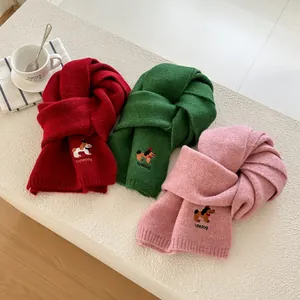 Dettaglio di sciarpe in maglia colorate con ricamo di cane carino in rosso, verde e rosa