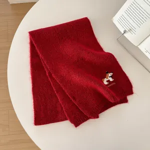 Dettaglio del ricamo a forma di cane su una morbida sciarpa in maglia mohair bordeaux