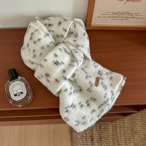 Dettaglio sciarpa di lana color crema a pois grigi con etichetta in pelle marrone