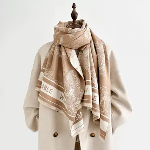 Detail of cashmere scarf featuring landscape print, tassel edges and lettered border