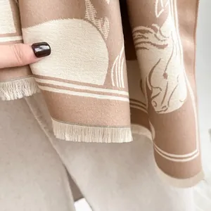 Macro detail of camel wool scarf showing horse jacquard pattern and fringe edges