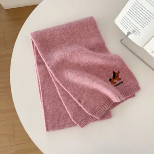 Dettaglio di sciarpa in maglia rosa con ricamo di cane e scritta cutedog testurizzata