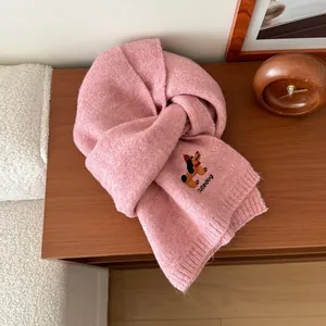 Dettaglio del ricamo di un cane carino e testo cutedog sulla sciarpa rosa in maglia