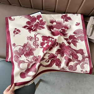 Close-up of vintage floral pashmina scarf with red borders and fringe on a leather surface