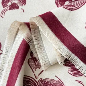 Close-up of bohemian scarf fringe detailing with red ethnic pattern on beige fabric