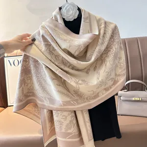 Detail of floral pattern on beige cashmere-like shawl with fringed edges and camellia decor