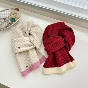 Detail of chunky knit scarves with colorful polka dots in cream and wine red colors