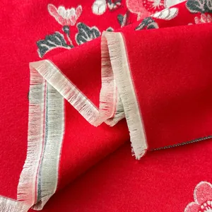 Dettaglio dello scialle rosso effetto cashmere con motivi floreali e frange delicate