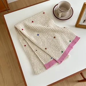 Detailed knit texture of a thick wool scarf featuring colorful dots and pink contrast edges