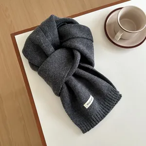 Detail of dark grey wool knit scarf with ribbed edges and premium texture on a white surface
