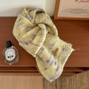 Dettaglio macro della sciarpa in lana mohair gialla e viola con etichetta in pelle