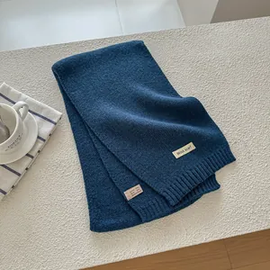 Detail of dark blue wool knit scarf showing fabric label with material composition