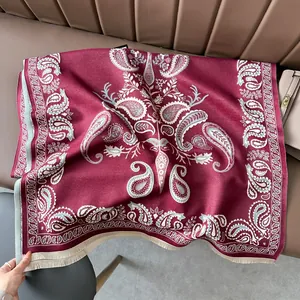 Detailed view of burgundy paisley pashmina scarf with soft fringes on leather background