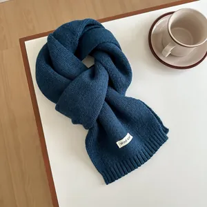 Detail of dark blue knitted wool scarf showing ribbed edges and thick texture on a table