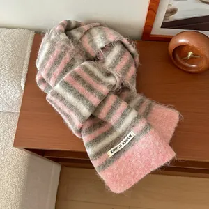 Gros plan d'une écharpe en laine rayée avec texture pelucheuse rose et grise et étiquette