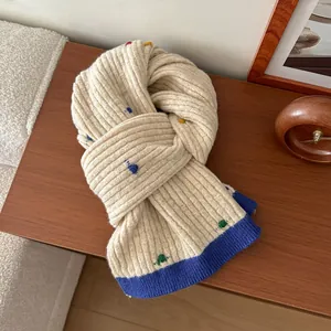 Close-up of knit wool scarf with colorful polka dots and blue contrast edge on wood desk