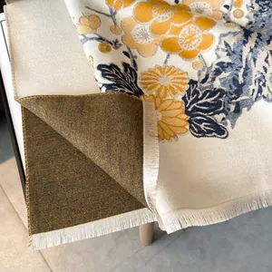 Dettaglio di una sciarpa jacquard con fiori di prugno, frange sottili e consistenza cashmere